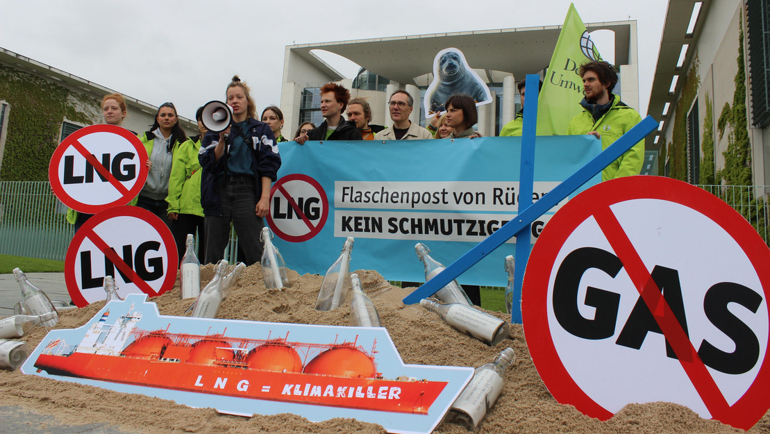 Eine Gruppe von Menschen, die sich gegen LNG-Terminals vor Rügen stark machen, mit Megaphone, Plakaten und Schildern