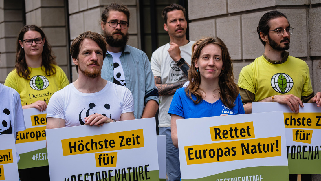 Personen halten Schilder mit der Aufschrift "Rettet Europas Natur"