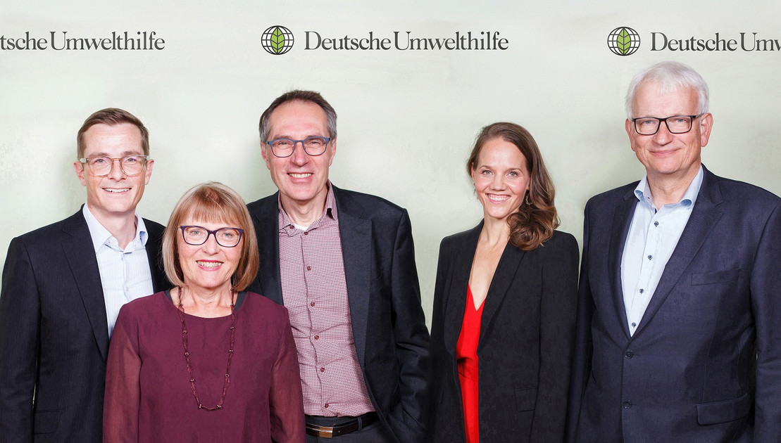 Eine Gruppe von Menschen steht vor einer Fotowand mit dem Logo der Deutschen Umwelthilfe