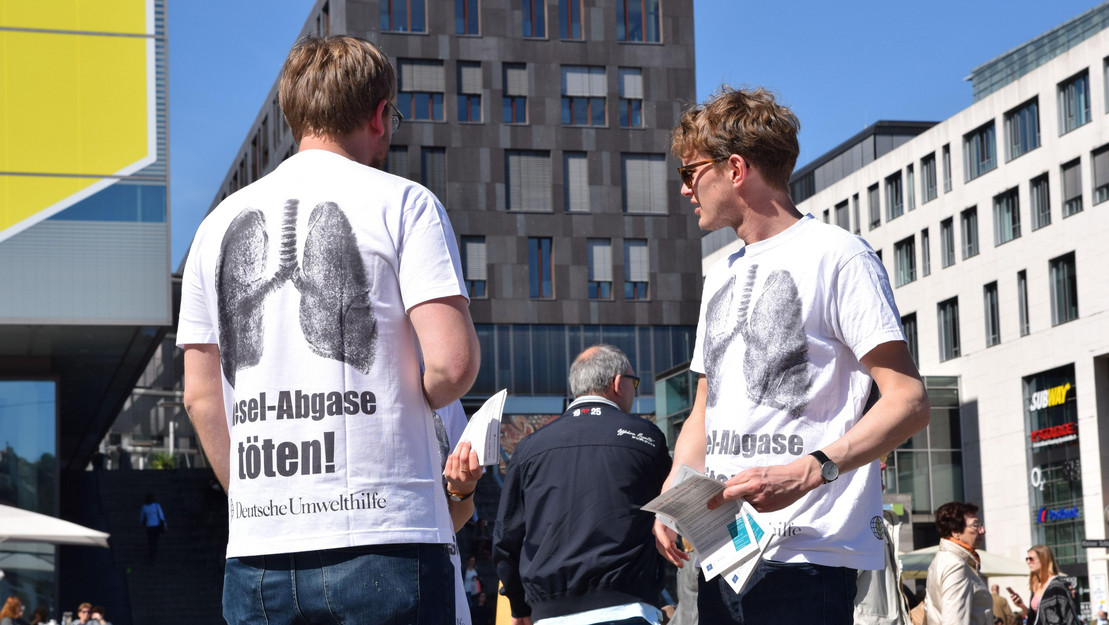 Personen, die Flyer verteilen und weißen T-Shirts mit der Aufschrift Dieselabgase töten.