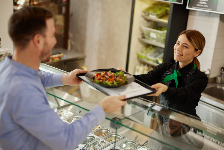 Mid adult man getting a custom salad made at a salad bar